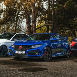 A blue Honda Civic Type R is parked outdoors among trees, showcasing a sporty look.